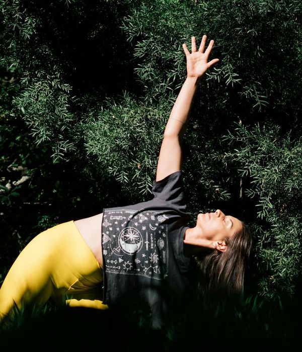 Woman in a dynamic yoga pose against a bright morning backdrop.